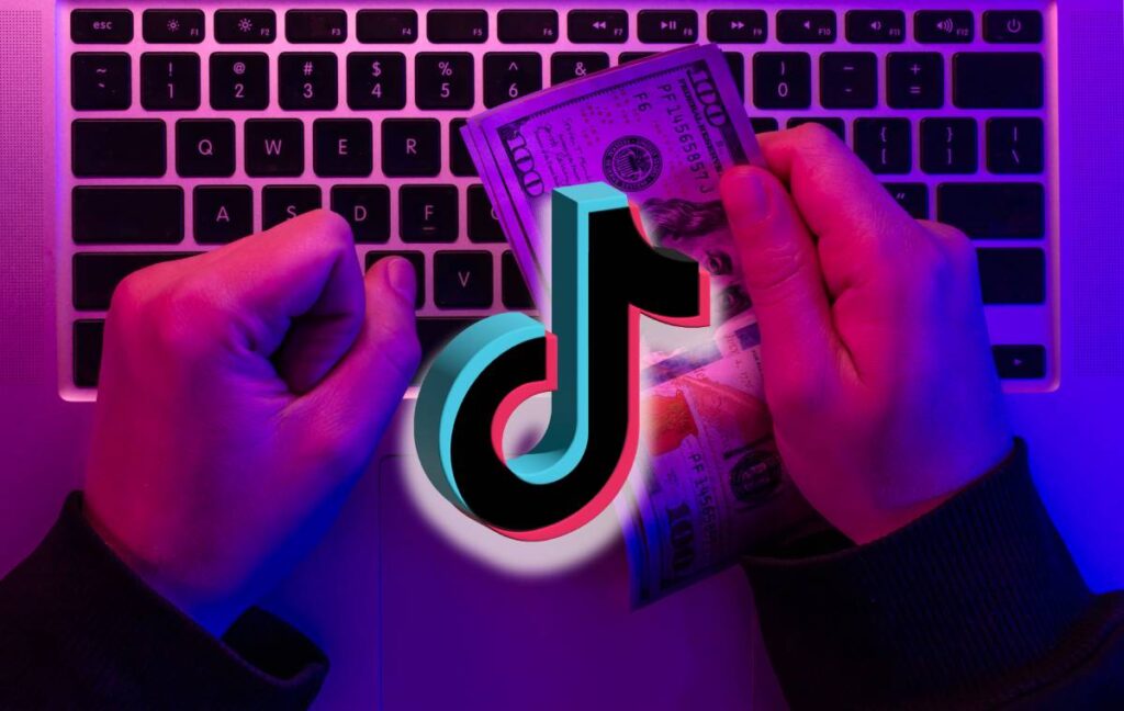 Como ganhar dinheiro no TikTok: O guia completo para monetizar em 30 dias 2 Mãos segurando notas de cem dólares com logo do TikTok sobre teclado de laptop, representando monetização na plataforma.