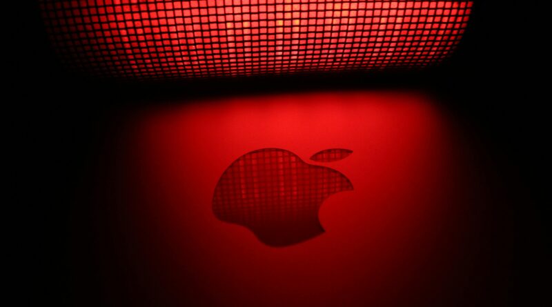 Artistic photo of a glowing apple-shaped graphic with a checkered pattern and red background.