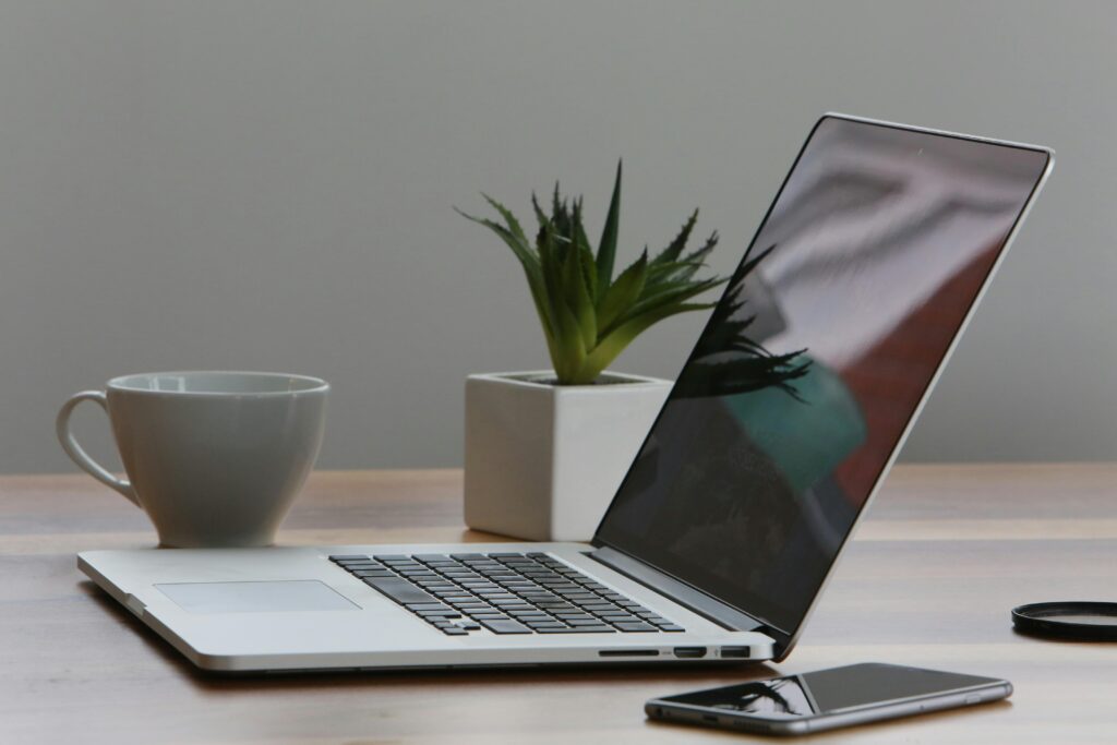 5 coisas essenciais ao comprar notebook para trabalho em 2025 5 Mesa de escritório minimalista com laptop, smartphone e planta para um ambiente de trabalho moderno.