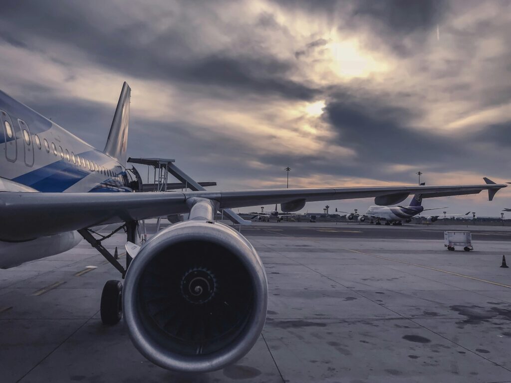 Um avião de passageiros está estacionado na pista ao pôr do sol, com outra aeronave ao fundo.