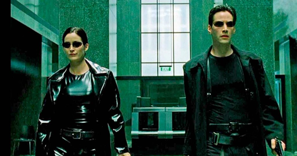 Cena icônica do filme Matrix com Neo na frente de códigos digitais, destaque para filmes sobre hackers e cultura pop