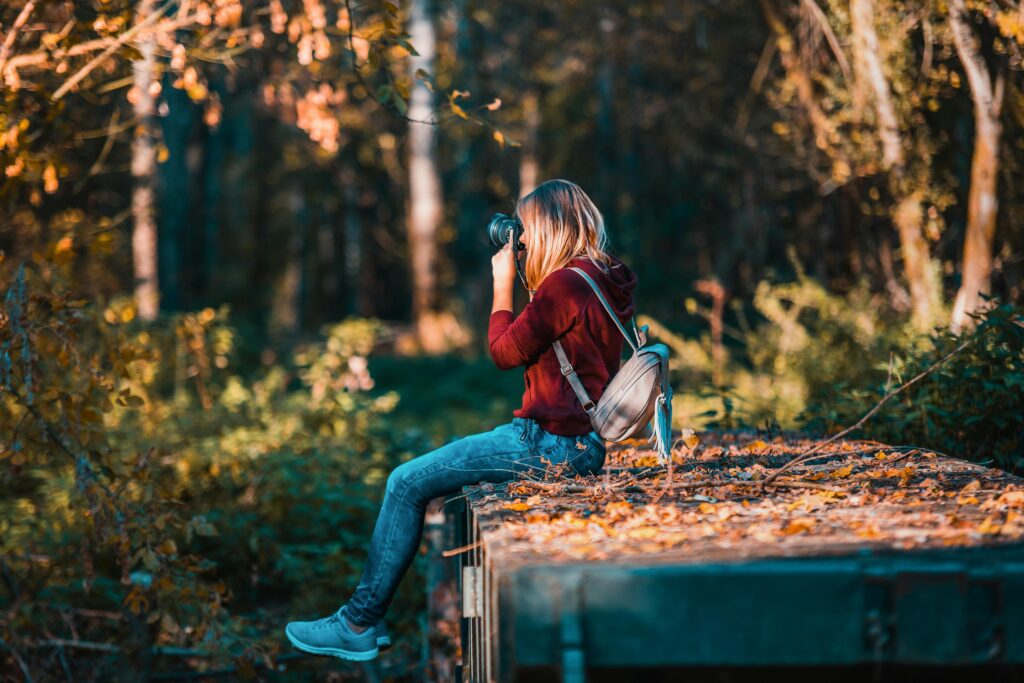 Transformar hobby em negócio: guia essencial 2 Young woman takes photos in a vibrant forest setting, embracing nature.