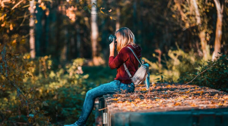 Young woman takes photos in a vibrant forest setting, embracing nature.