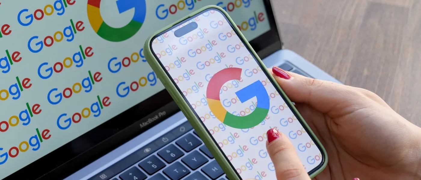 Mulher olha para celular exibindo o logo do Google, com logo do Google em monitor ao fundo; lançamento do Fontes Preferidas em agosto de 2025 nos EUA e Índia.