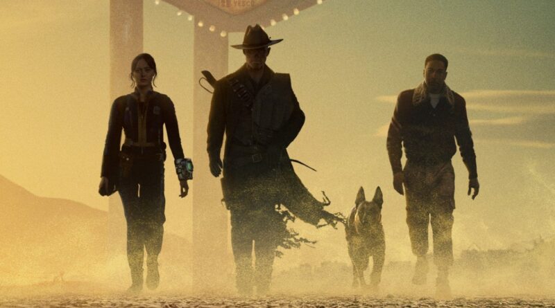 Pôster oficial de Fallout 2 com Lucy MacLean, The Ghoul, Maximus e Dogmeat às portas de New Vegas. Destaque para a atmosfera desértica e ameaçadora do novo cenário.