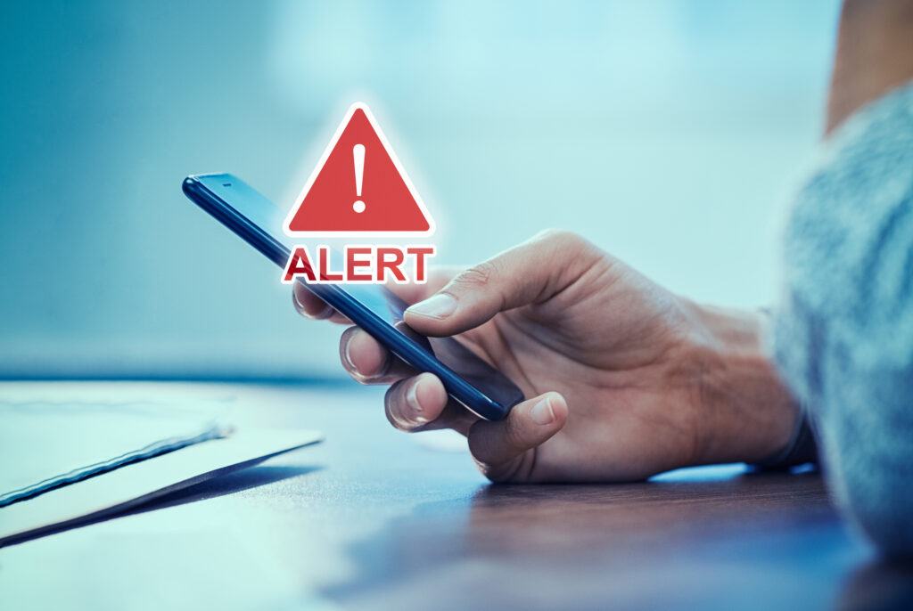 Anatel alerta: Mão segurando controle remoto com estampa de caveira sobreposta. Situação de risco representada ao usar TV boxes não homologadas no Brasil, foco em pirataria e infecção por malware Bad Box 2.0.