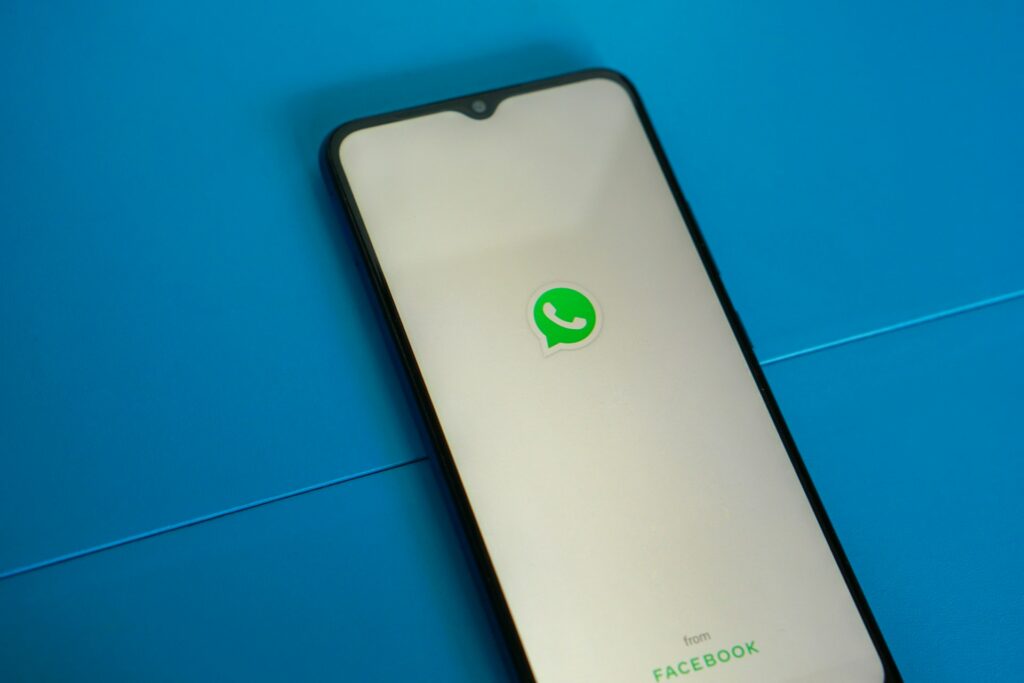 WhatsApp muda convites e facilita entrada em grupos 2 Ilustração mostra duas pessoas usando celular ao lado de um smartphone com bate-papo do WhatsApp na tela,