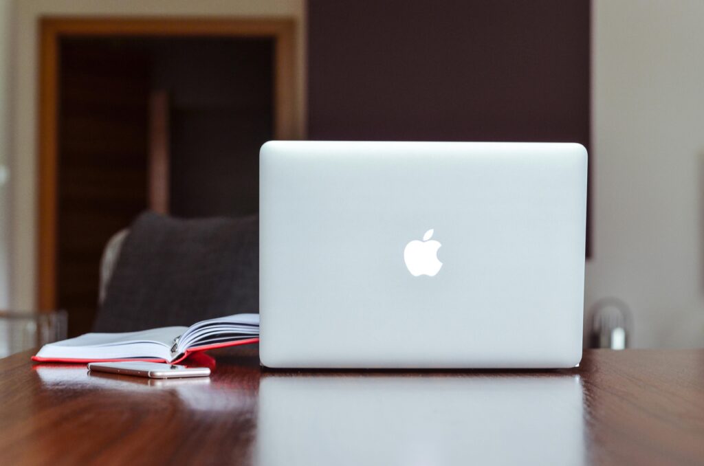 MacBooks pegam vírus: proteção não é infalível 2 MacBooks pegam virus: A clean and modern workspace featuring a laptop, book, and smartphone on a wooden table.