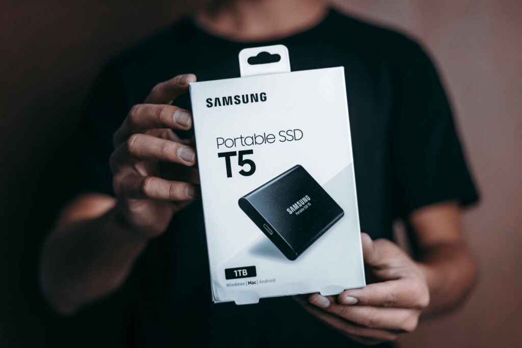 SSD usado vale a pena? 5 cuidados essenciais 3 Close-up of a person holding a Samsung T5 Portable SSD box, emphasizing modern technology.