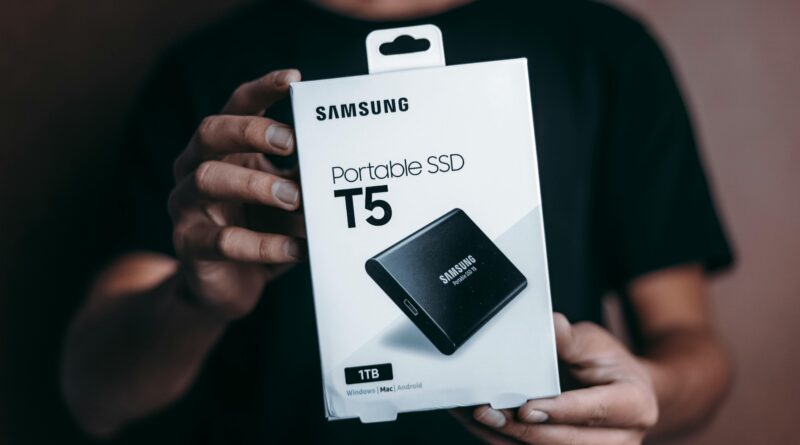 Close-up of a person holding a Samsung T5 Portable SSD box, emphasizing modern technology.