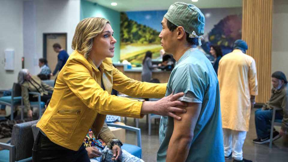Carol segura um médico com expressão preocupada em uma cena de Pluribus