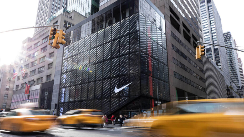 Loja da Nike em Nova York com a marca visível na fachada e carros passando na rua