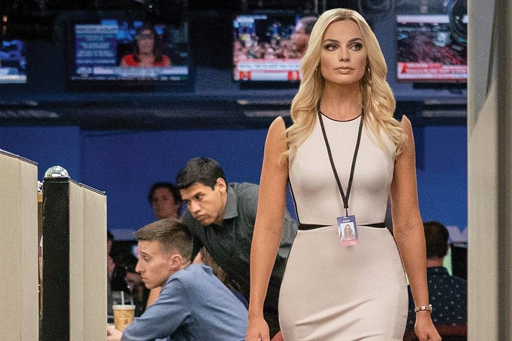 Margot Robbie como Kayla Pospisil em Bombshell com visual corporativo e maquiagem impecável