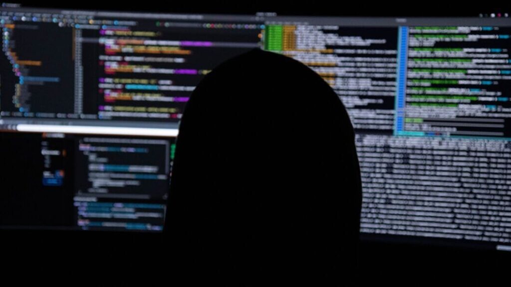 Programador operando código em ambiente escuro, simbolizando ataques cibernéticos