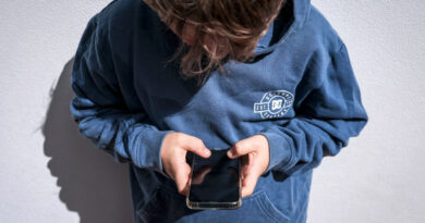 Imagem de um adolescente olhando o celular; ilustrando o uso de redes sociais por menores.