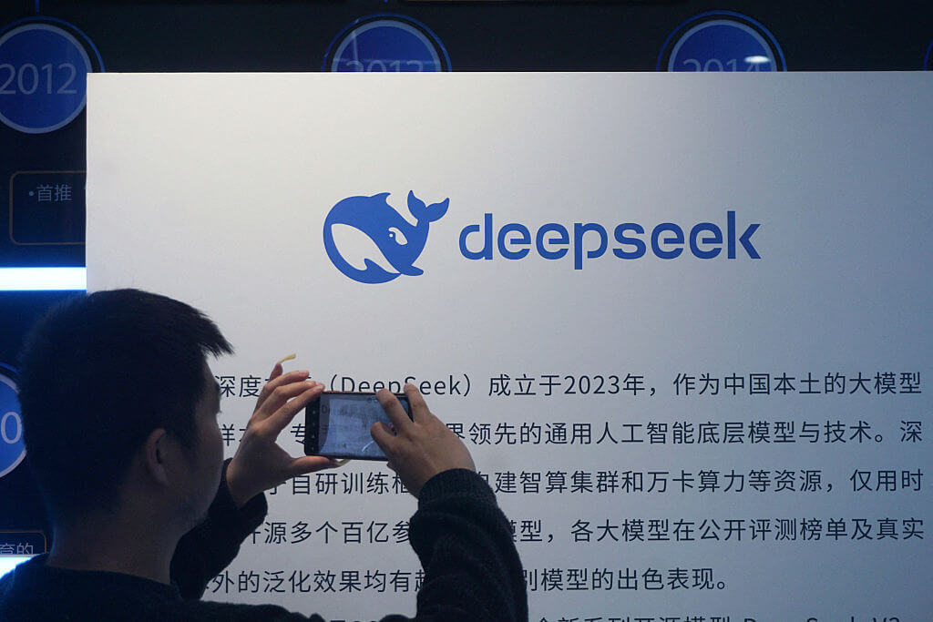 Homem fotografa um display DeepSeek em Hangzhou, simbolizando o avanço da IA na China.