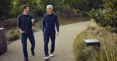 John Ternus e Tim Cook sorrindo e caminhando lado a lado.