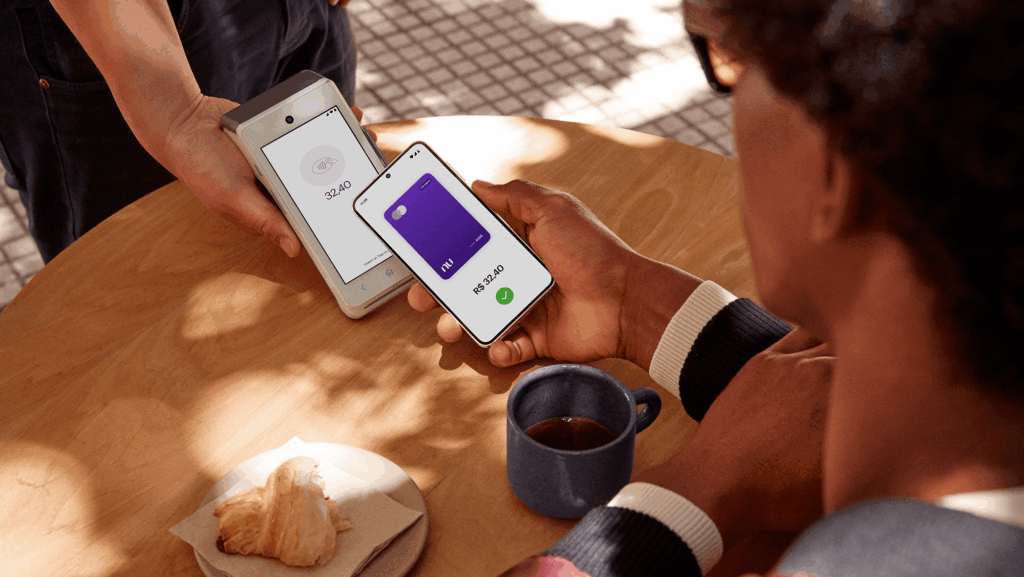 Pessoa aproximando celular de maquininha de cartões para pagar com o Nubank