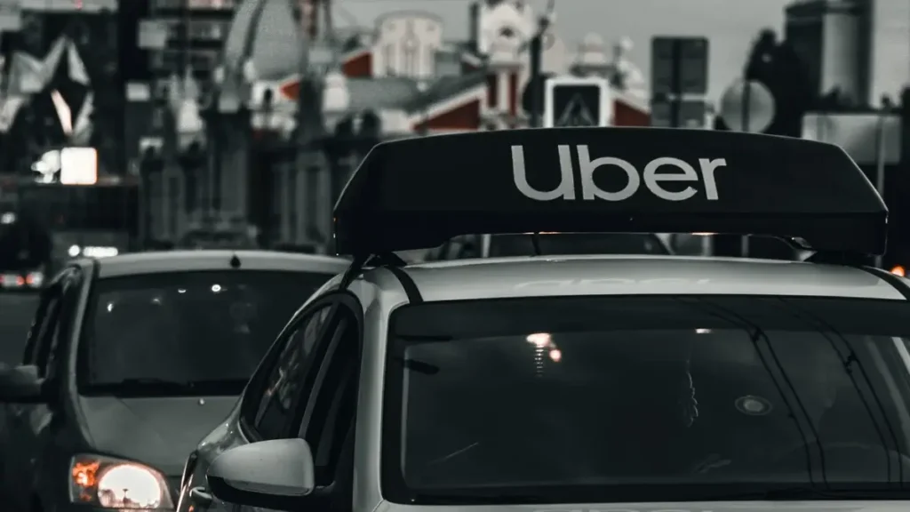 Logo da Uber em carro ilustra reestruturação, demissões e trabalho remoto